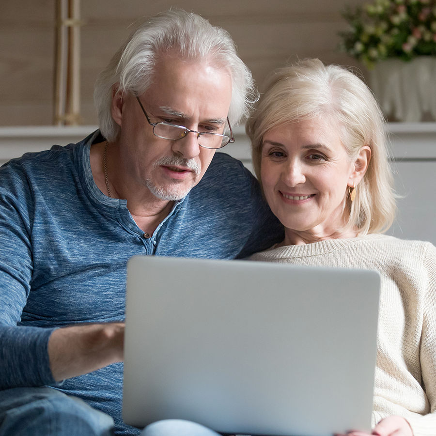 Man en vrouw kijken naar laptop op bank
